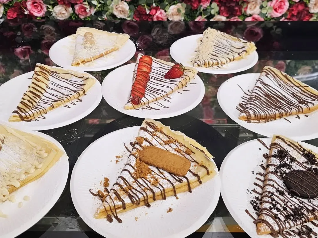 Nove crêpes pronte sul banco davanti al muro di fiori